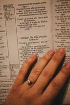 A woman's hand on the pages of a Bible. 