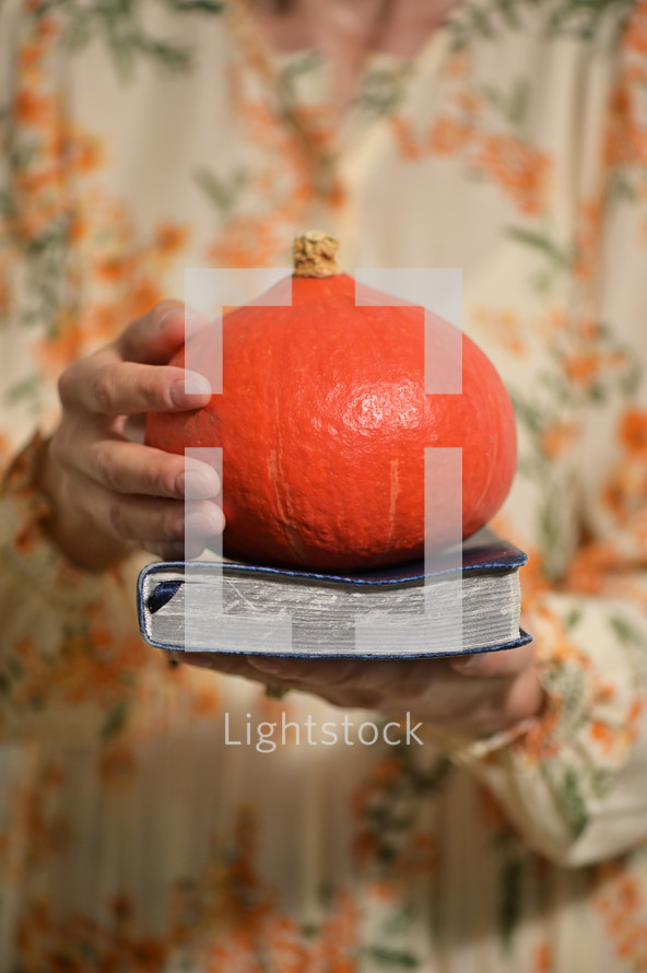 a woman holding a Bible and a pumpkin 