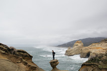 a man standing alone on a rock formation near the ocean 