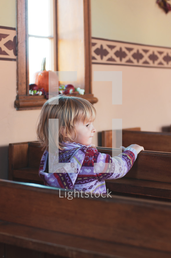a child sitting in church pews 