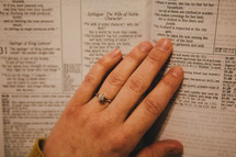 A woman's hand on the pages of a Bible. 