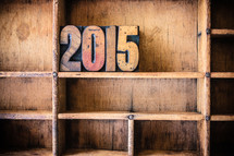 Wooden letter spelling "2015" on a wooden bookshelf.