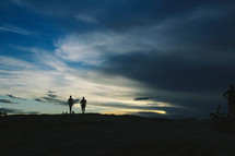 silhouettes of people standing on a mountain top 