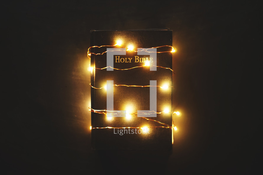 a Bible wrapped in fairy lights 