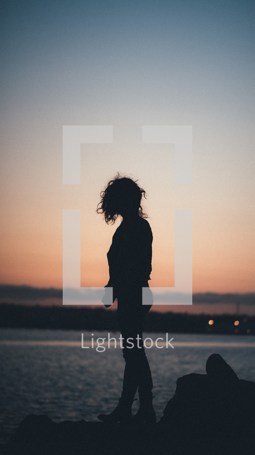 silhouette of a woman on a beach at dusk 