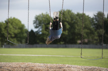 A little girl swinging on the playground.
