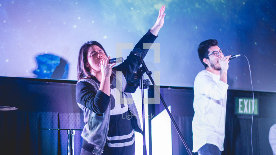 worship leaders performing on stage in front of a projection screen