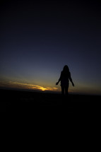 silhouette of a woman at sunset with palms up 