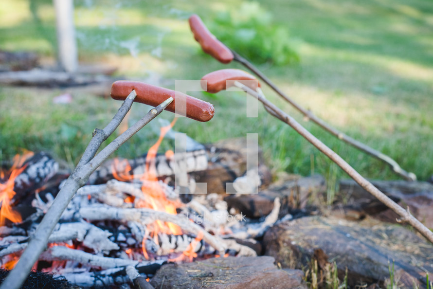 cooking hotdogs over a fire 