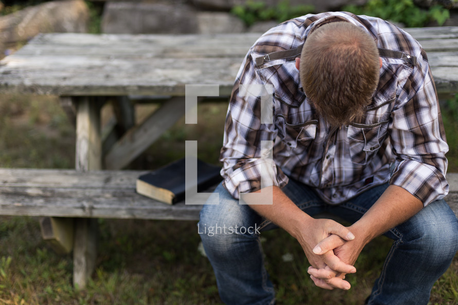 a man praying at a picnic table 
