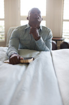 a man in prayer at the side of a bed 