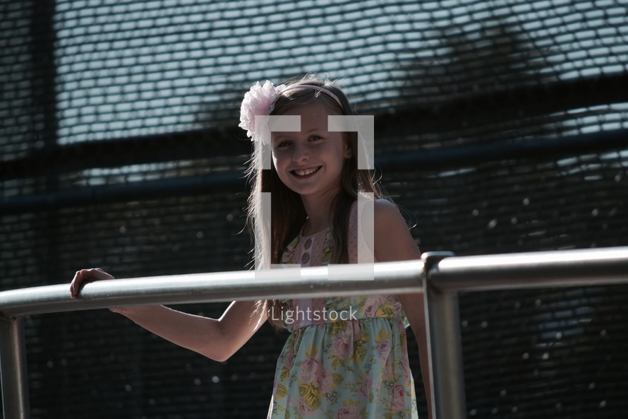 smiling girl with her hand on a railing 