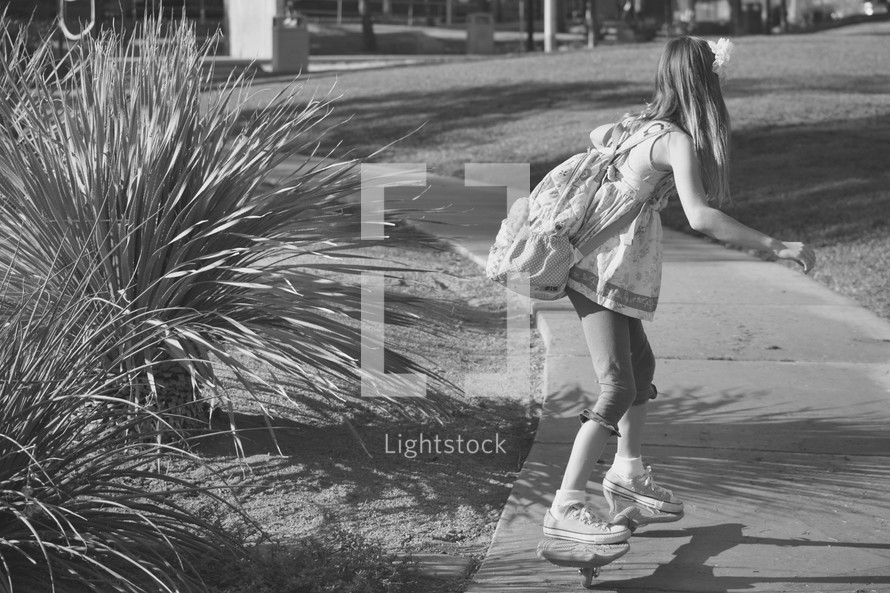 a little girl on a ripstick with her book bag on 