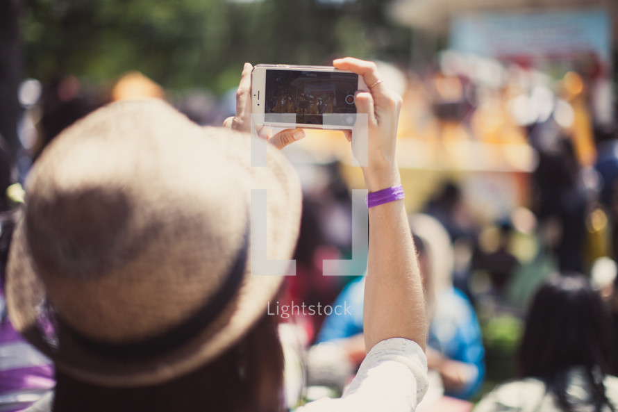 woman in a straw hat taking a picture with her cellphone 