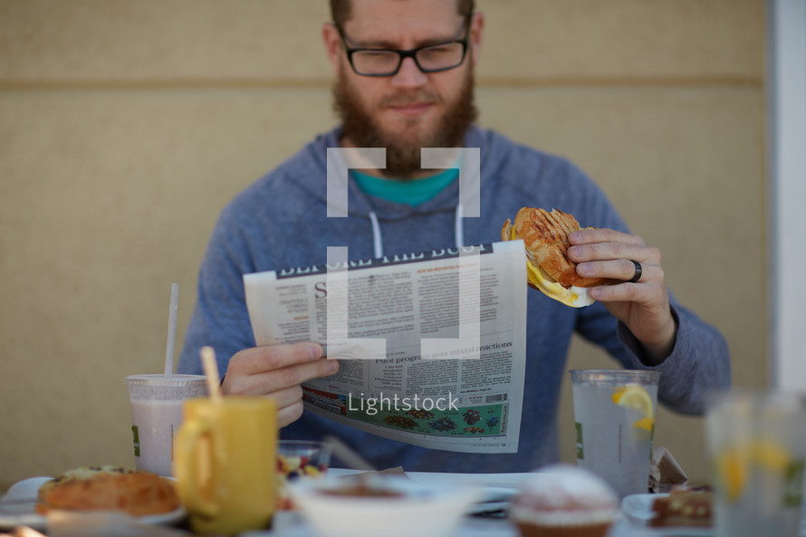 a man reading a newspaper over breakfast 