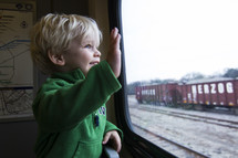 toddler boy waving on a train 