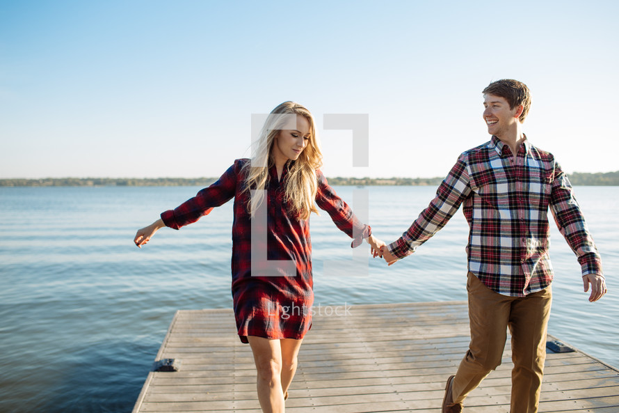 a couple holding hands on a dock 