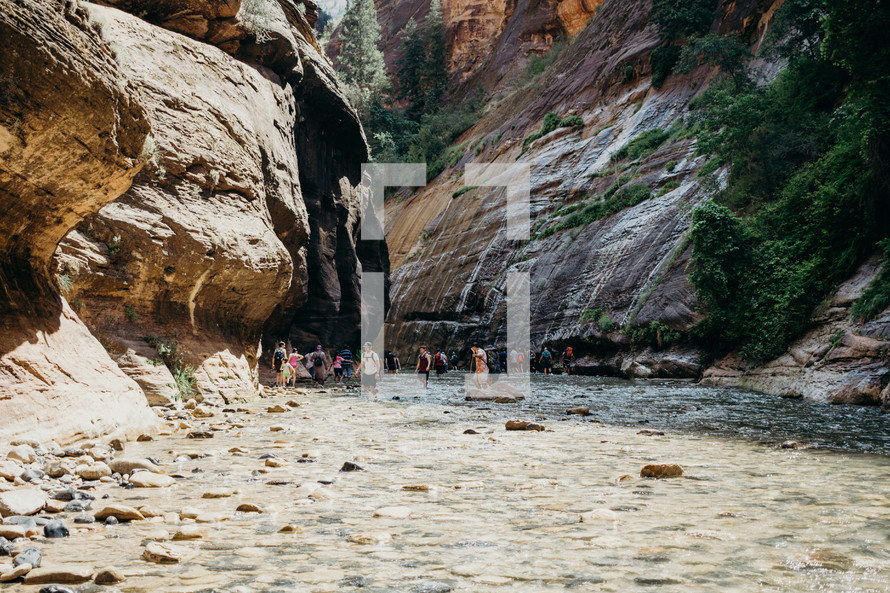 people hiking through a river 