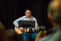 a man playing a guitar during a worship service 