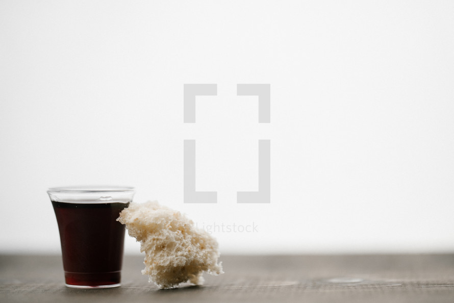 communion wine in a cup and bread on wood