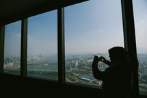 a woman taking a picture from a skyscraper window 