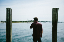 A man standing on a dock looking out at a harbor 