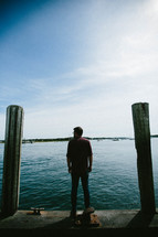 a man standing on a dock looking out at a harbor 