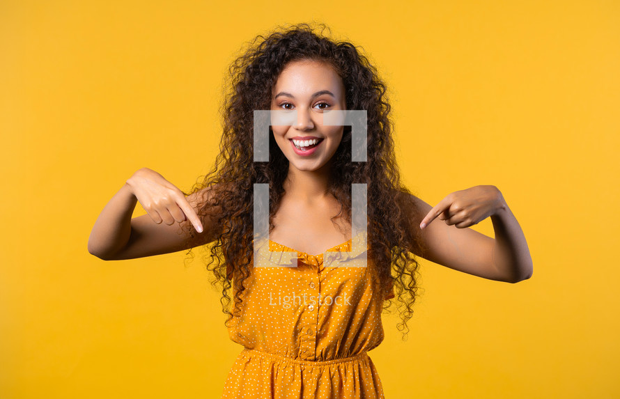 Pretty woman pointing down to advertising area. Blue background. Young lady asking to click to subscribe below. Copy space for your commercial idea, promotional content. High quality photo