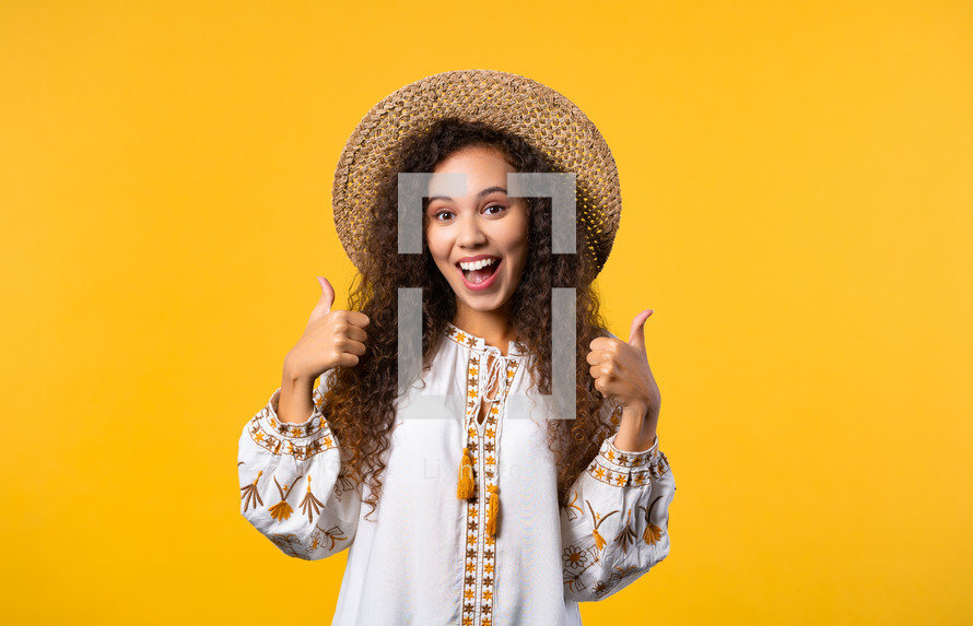 Positive ukrainian woman makes like hand sign, thumbs up gesture. Happy girl, correct perfect choice, great deal, yellow background. Positive lady smiles to camera, approval, trust concept. 