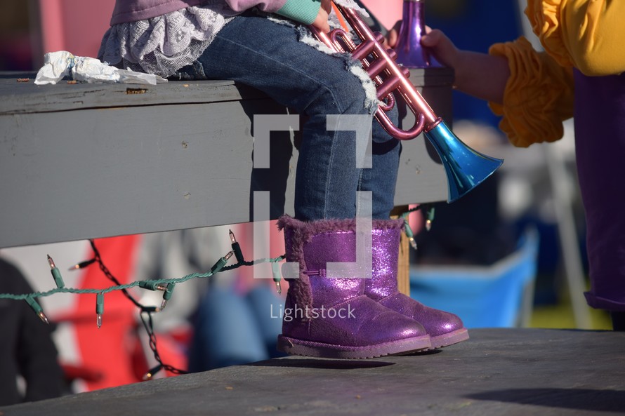 feet of a little girl sitting on homemade bleachers waiting on a parade 