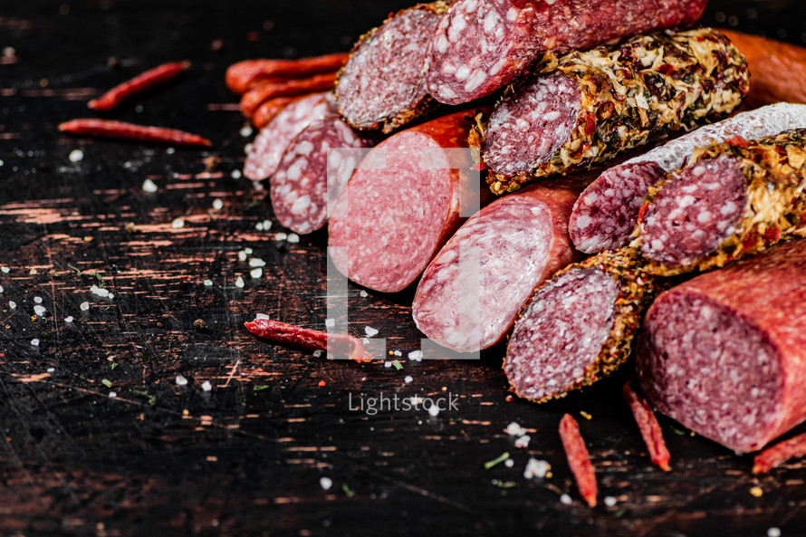 Assortment of various aromatic salami sausages. Against a dark background. High quality photo