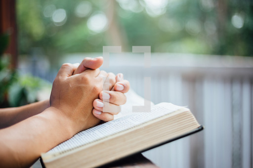 Praying hands over pages of a bible — Photo — Lightstock