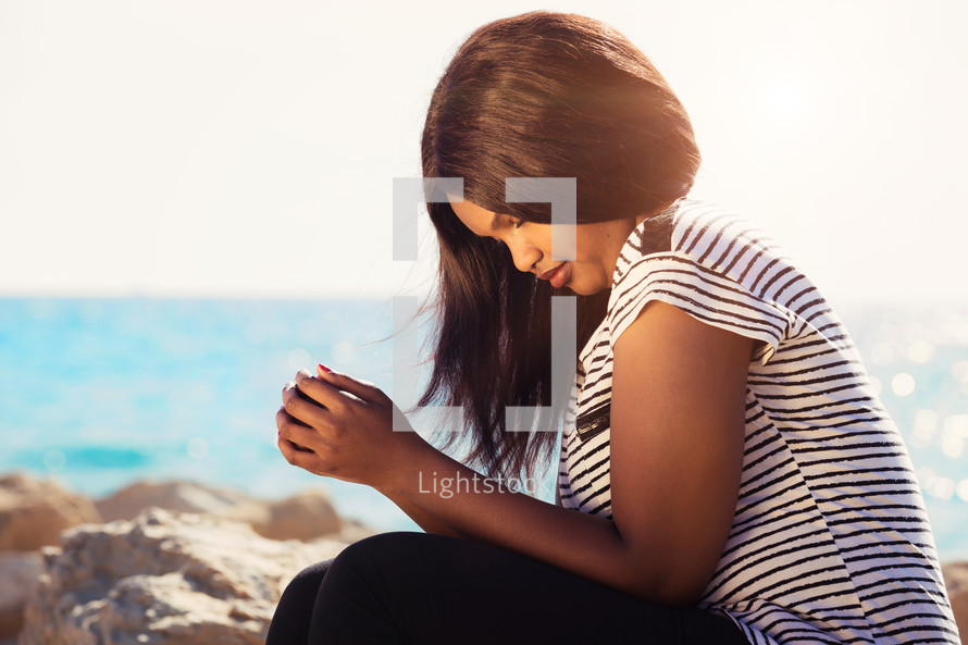 woman in prayer on a beach 