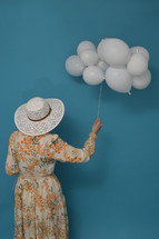 Cloudy day. Concept with woman and white balloons against blue sky