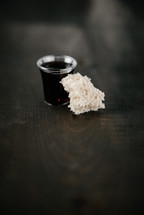 communion wine in a cup and bread on wood background 