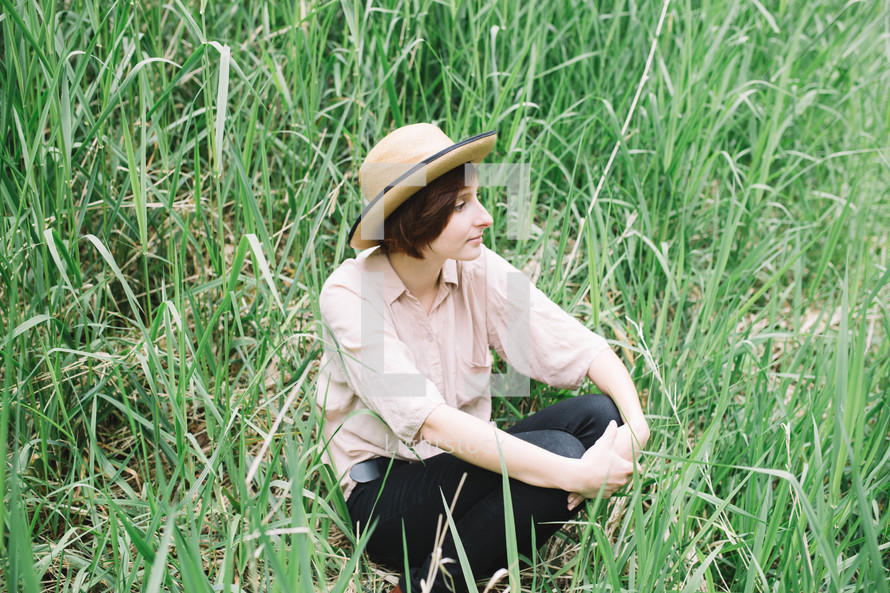 woman in a straw hat sitting in grass