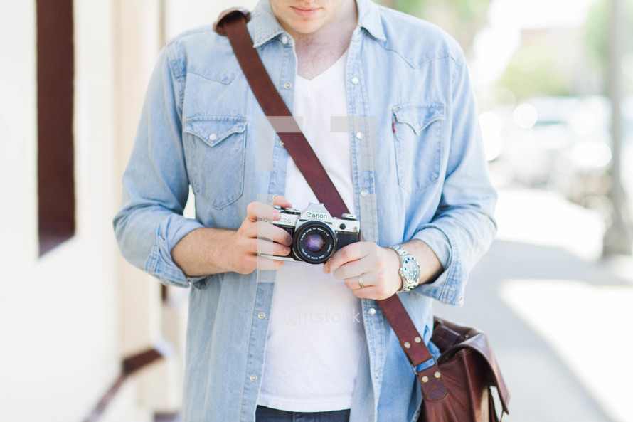 man holding a camera and shoulder bag