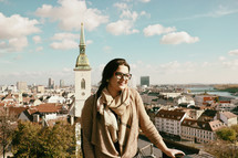 a woman standing in front of a view of a European city 