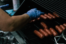 a man cooking sausage on a grill 