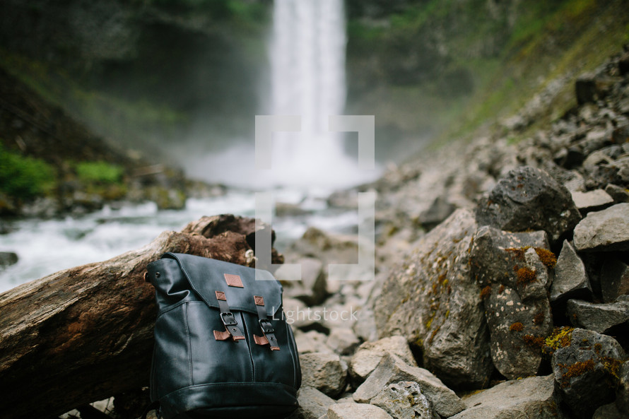 a backpack on rocks near a waterfall