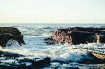 ocean water washing over rocks along a shore 