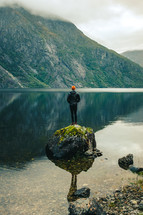 a man standing on a rock in the middle of a lake taking in the views