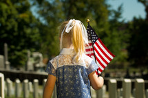 a girl child carrying an American flag 