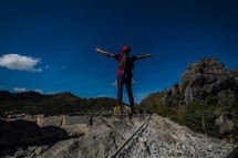 a man standing on a mountaintop with outstretched arms 
