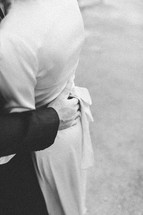 Close up of a groom's hand on the small of his bride's back.