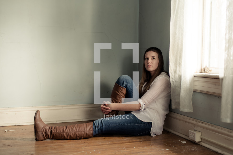 sad teen girl sitting in an empty room 
