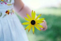 toddler girl holding a yellow flower 