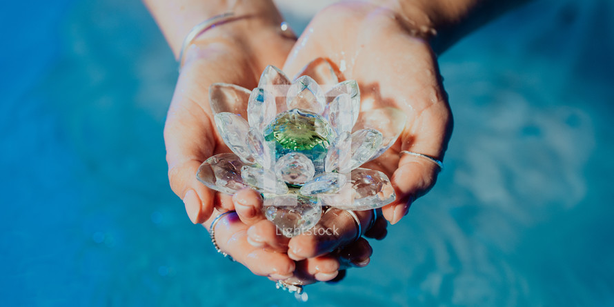 Woman holding fragile lotus flower. Clean water drops are dripping from crystal. Concept of religion, kundalini, meditation, chakras, spiritual inner world. High quality photo