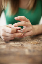 A woman taking her wedding ring off her finger. 
