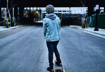a boy skateboarding in the middle of a street 